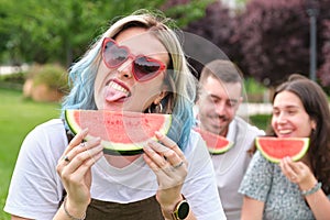 Happy young woman sticking out her tongue holding a piece of watermelon