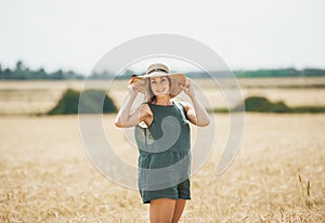 Happy young woman in straw hat enjoying sun on wheat field