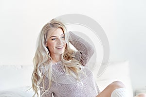 Happy young woman stretching in bed at home