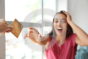Happy young woman stretching hand for credit card
