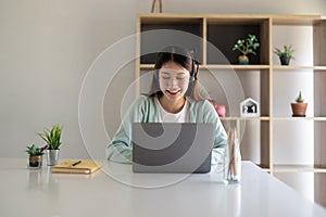 Happy young woman studying online, watching webinar, podcast on laptop. E-learning concept