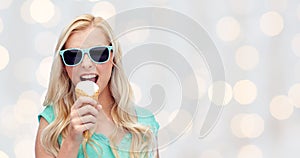 Happy young woman in sunglasses eating ice cream