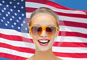 Happy young woman in sunglasses over american flag