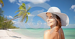 Happy young woman in sunhat over summer beach