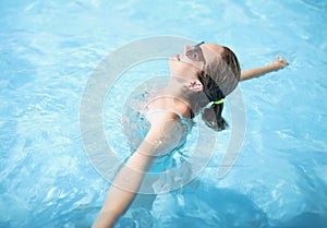 Happy young woman swim in pool, enjoy sun, sunbathe in water, relaxing atmosphere