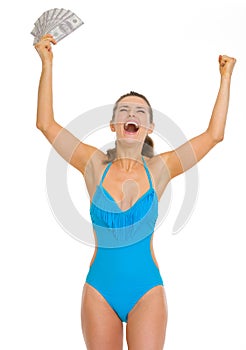 Happy young woman in swimsuit with fan of dollars