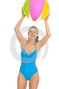 Happy woman in swimsuit playing with beach ball