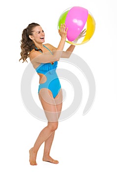 Happy young woman in swimsuit playing with beach ball