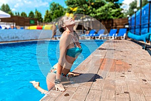 Happy young woman in swimsuit posing in hotel pool. Attractive slim lady with smooth skin smiling in water pool