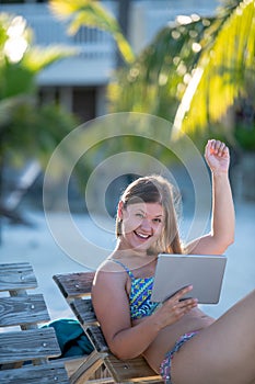Happy young woman with tablet on the beach