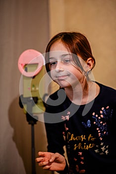 Happy young woman taking selfie on white background. Girl takes a video of herself with a monopod or selfie stick