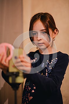 Happy young woman taking selfie on white background. Girl takes a video of herself with a monopod or selfie stick