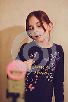 Happy young woman taking selfie on white background. Girl takes a video of herself with a monopod or selfie stick