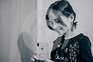 Happy young woman taking selfie on white background. Girl takes a video of herself with a monopod or selfie stick