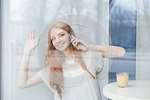 Happy young woman talking on mobile phone in cafe