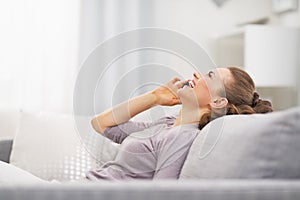 Happy young woman talking mobile phone while relaxing on couch