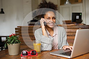 Happy young woman talking on phone at home