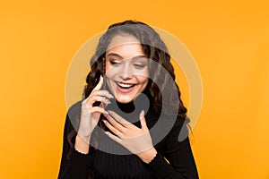 Happy young woman talking phone  over the yellow background.