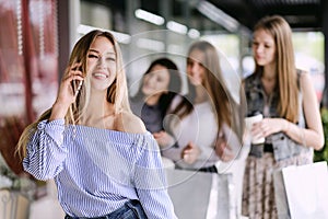 Happy young woman talking on the phone in shopping mall