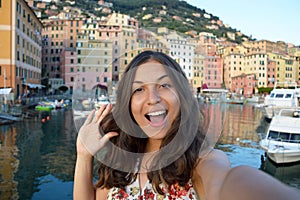 Happy young woman tanned taking selfie photo in a typical italian landscape with harbour and colorful houses for italian holidays