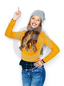Happy young woman or teen girl pointing finger up