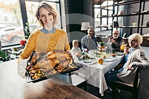 happy young woman with thanksgiving turkey for holiday dinner with family and looking