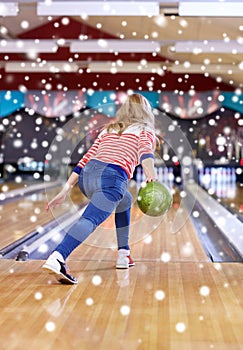 Happy young woman throwing ball in bowling club