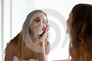 Happy young woman touching under eyes area after morning showering. photo