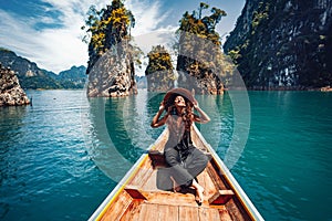 Happy young woman tourist in asian hat on the boat at lake