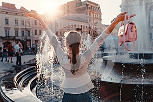 Happy young woman tourist looks at fountain. Summer travel. Vacation and holidays concept