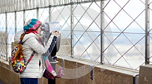 Happy young woman tourist at the observation deck of Empire State Building in New York City. Female traveler enjoying the view of