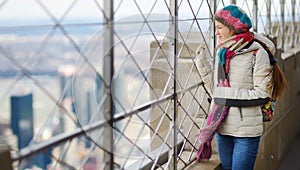 Happy young woman tourist at the observation deck of Empire State Building in New York City. Female traveler enjoying the view of