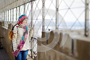 Happy young woman tourist at the observation deck of Empire State Building in New York City. Female traveler enjoying the view of