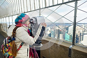 Happy young woman tourist at the observation deck of Empire State Building in New York City. Female traveler enjoying the view of