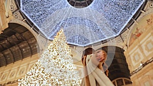 Happy young woman turns around herself on the background of Christmas tree in the Vittorio Emanuele II gallery