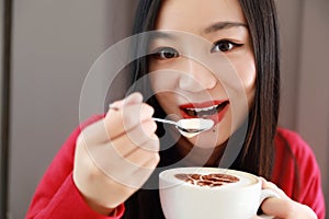 Happy young woman is under a blanket and cup of coffee on winter morning at home