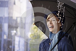 Happy young woman under umbrella in rain