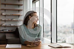 Happy young woman use cellphone in office thinking