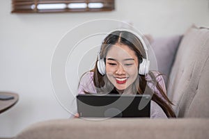 Happy young woman using laptop at home sitting on soft couch. Lady is working on laptop computer. Girl student is typing