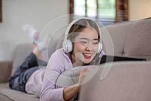 Happy young woman using laptop at home sitting on soft couch. Lady is working on laptop computer. Girl student is typing