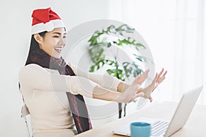 Happy young woman using laptop in  video call and celebrating christmas hoilday