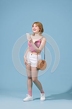 Happy young woman using mobile cell phone walking going isolated on pastel blue background studio portrait