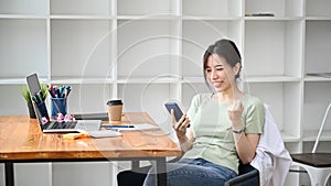 Happy woman using smartphone and celebrating success.