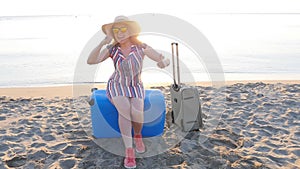 Happy young woman on vacation with a suitcase showing thumbs up