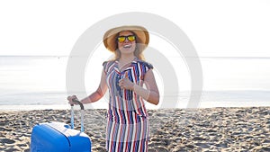 Happy young woman on vacation with a suitcase showing thumbs up