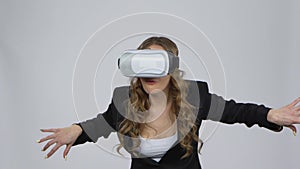 Happy young woman with virtual reality headset or 3d glasses on gray background at studio.