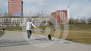 Happy young woman walking along the road with her german shepherd dog. German puppy.Slow motion