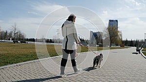 Happy young woman walking along the road with her german shepherd dog. German puppy.Slow motion