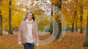 Happy young woman walking in autumn park