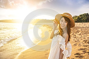 Happy young woman walking  on the beach at sunset